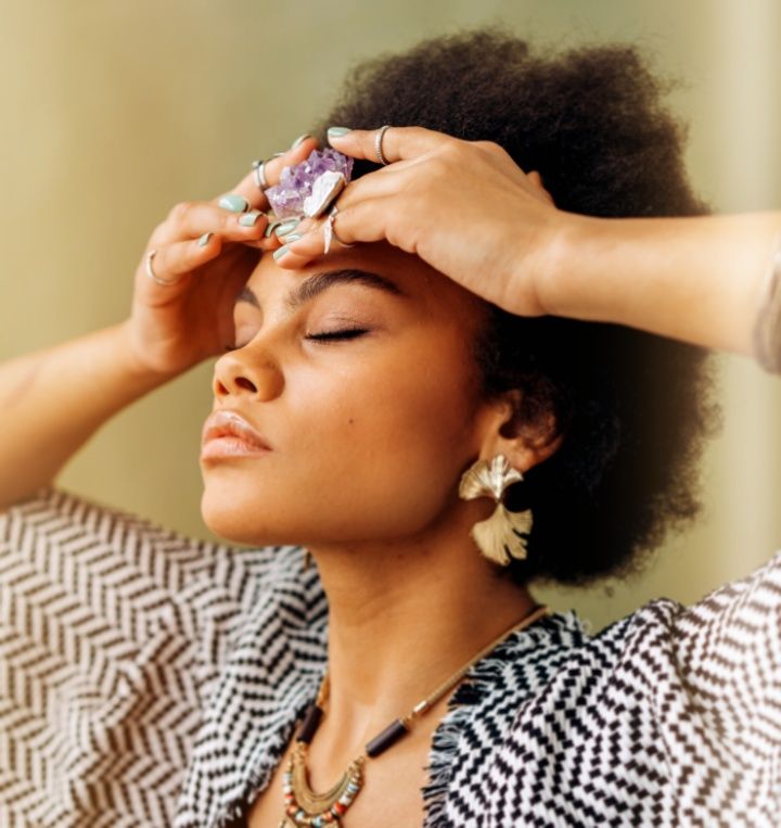 Woman holding amethyst on the crown chakra