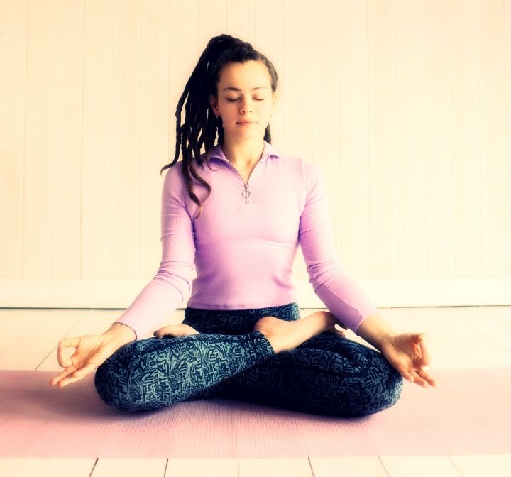 Woman in lavender outfit seated in meditation.