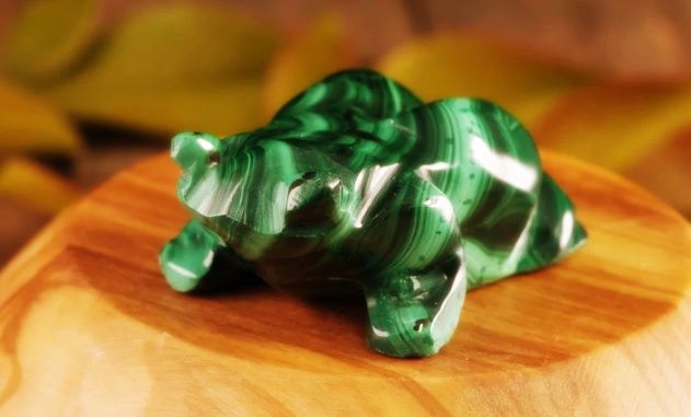 Frog sculpted from malachite stone sitting on a table