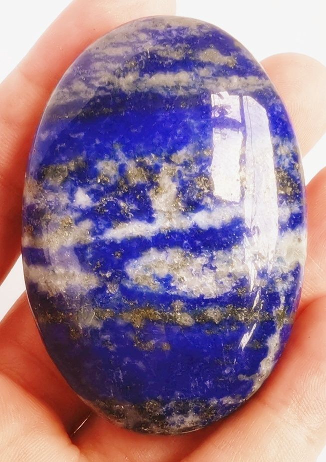 Lapis lazuli oval shaped palm stone held in the hand